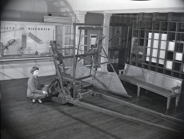 State Historical Society employee Joyce Hancock examines a replica of Cyrus McCormick's first reaper.