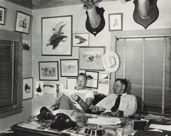 T.R. Moudler, manager of IH San Antonio motor truck district sitting next to "Jess." The men are likely in the office of an International Harvester dealership.