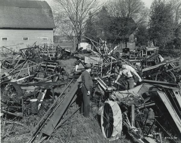 Men from George Schubert and Sons, an International Harvester dealership, examine old farm machines to identify candidates for a wartime scrap drive. The man at left is likely George Schubert.