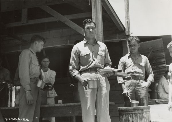 Group of men at field kitchen at Camp Elliot. According to the original caption, the man "with loaded mess kit is Derwood W. Hooper, Second Medical Detachment (Navy) attached to Marines at Camp Elliot."