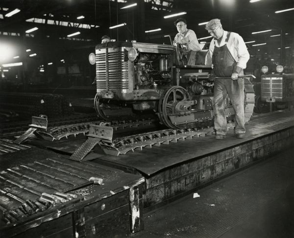 Factory workers assemble "shoe chains" on an International crawler tractor (TracTracTor) at International Harvester's Tractor Works.