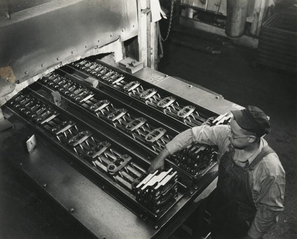 Factory worker hardening links for crawler tractors at International Harvester's Tractor Works.