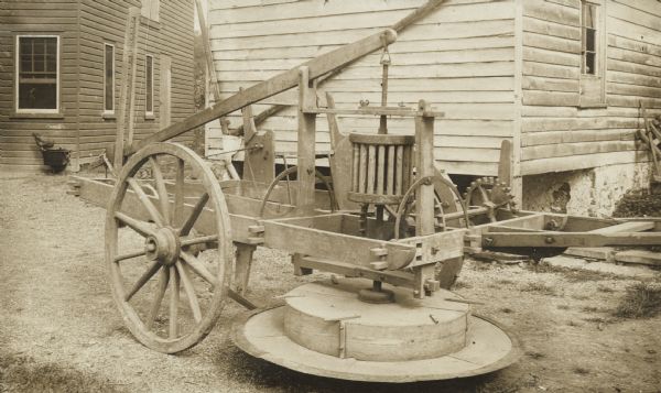 Mowing machine designed by Jabez Baily in a yard near a house or farm building.