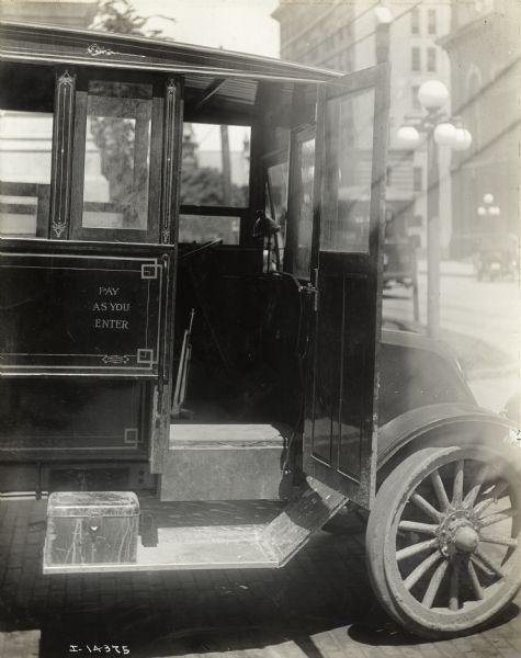 International Model F or 31 truck used for public transportation parked in urban area. Next to the open door on the side of the truck it reads: "Pay As You Enter."