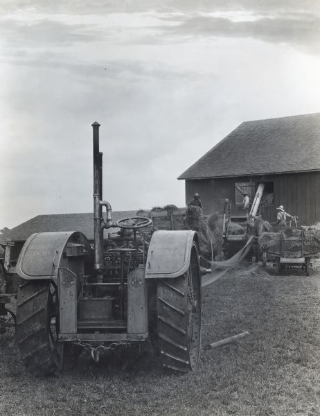 Men load hay into a barn with the help of an International 15-30 tractor.