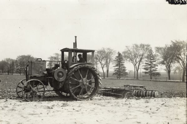 Man uses a Titan 15-30(?) tractor to plow a snow-covered field.
