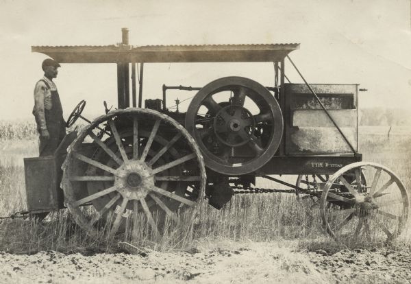 Side view of man at the wheel of his Titan Type D tractor in a field.