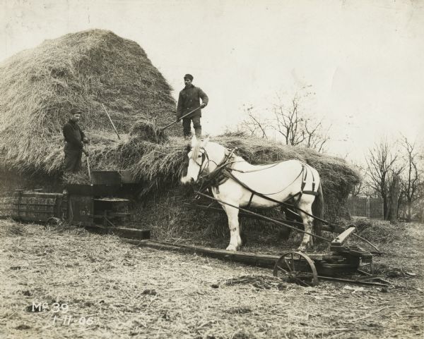 Men bale hay with a horse-powered hay press.