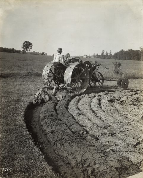 A man plows curved furrows in a field with a Mogul 8-16 tractor.