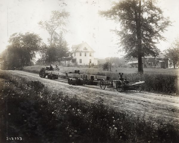 Mogul 8-16 tractor pulling a house moving rig on rural road. The rig is labled: "A.T. Coffin House Moving."