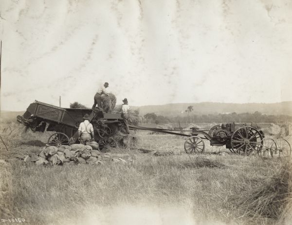 Men use Mogul 8-16 tractor to power a Butterworth self-binding thresher.
