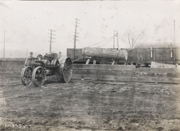 Mogul tractor is used to power a lifting outfit to load large logs onto freight car.