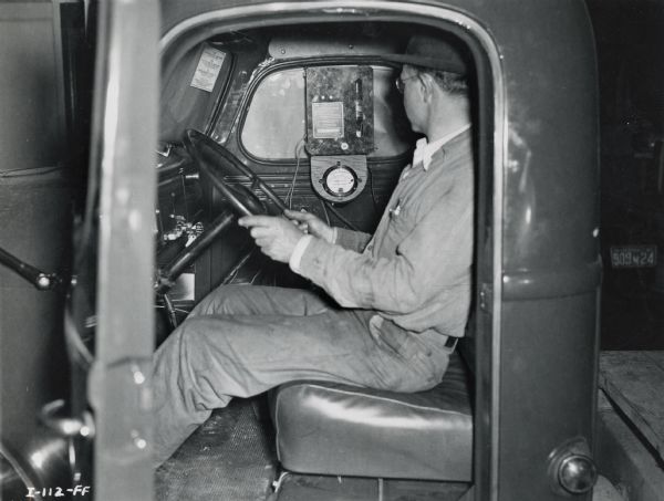 "Fuel consumption testing device." A factory worker sits in the cab of an International truck at the company's Ft. Wayne Works.