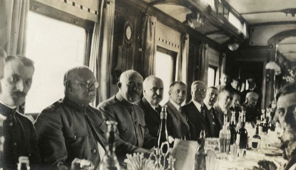 Root Commission members seated at a long table in a dining car of the Imperial train of the Ex-Czar Nicholas.