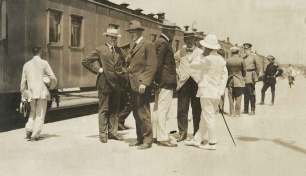 Men standing at a train station in Harbin, Russia (now China). Original caption identifies the men as follows: "Dr. Mott, Mr. Moran, Mr. [?] (YMCA Gen'l Secy in China), Mr. McCormick, Mr. Payson, Col. Mott, and General Horwaeth." Cyrus McCormick, Jr. is standing fifth from the left, facing the camera with white coat and straw hat.