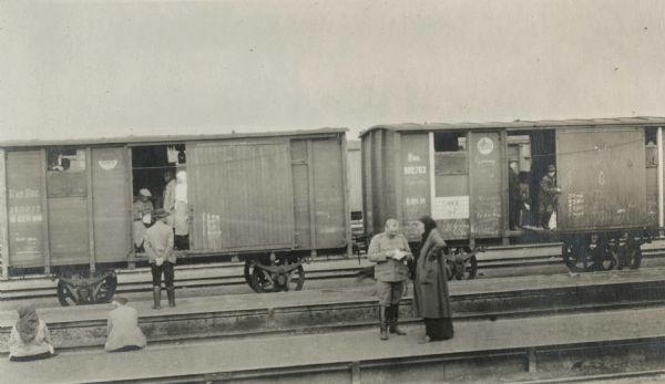 Men and women wait in boxcars and on the platform at a Russian railroad station. The original caption reads: "uppers and lowers on the Trans-Siberian Ry. [Railway]."
