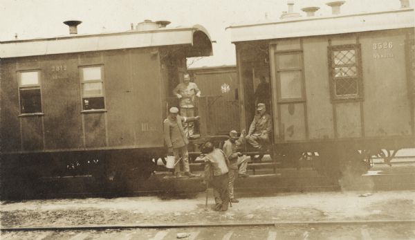 German prisoners around a train car at a Russian railroad station. One of the men is on crutches. The original caption reads: "German prisoners at work on the Trans-Siberian Ry. [Railway]."