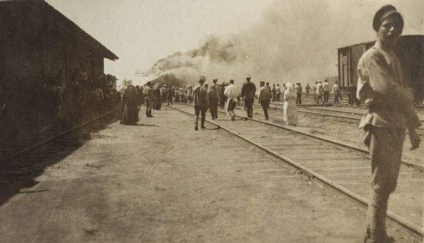 Crowd at a train station in Vyatka, Russia. Smoke in the background is coming from a burning railway ice-house.