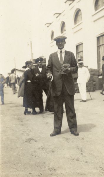 Well-dressed man standing holding cigarette and newspaper. Original caption reads: "Mr. Gorbatenko secretary Chinese Eastern Ry. [Railway]."