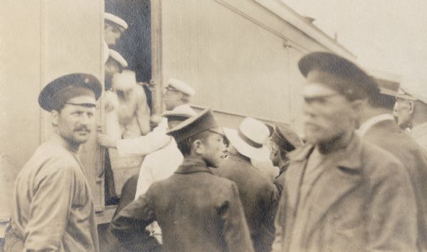 Uniformed men gathered around a train car somewhere along the Trans-Siberian railway in China. Original caption reads: "Chinese customs officials searching for opium on special train."