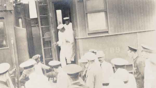 Uniformed men gathered around a train car somewhere along the Trans-Siberian railway in China. Original caption reads: "Chinese custom officials confiscating opium from special train."