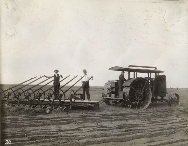 Men use a Mogul 15-30(?) tractor and a large gang plow in a field.