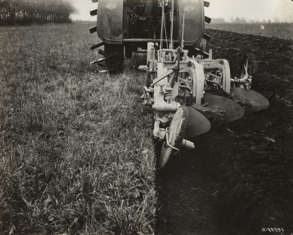 Close-up of a P&O three-bottom tractor plow pulled through field by a Titan 10-20 tractor.