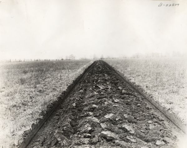 View to horizon of a plowed strip of earth in a farm field.