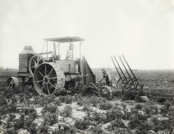 Man in a farm field with a Rumley tractor and a P&O plow.