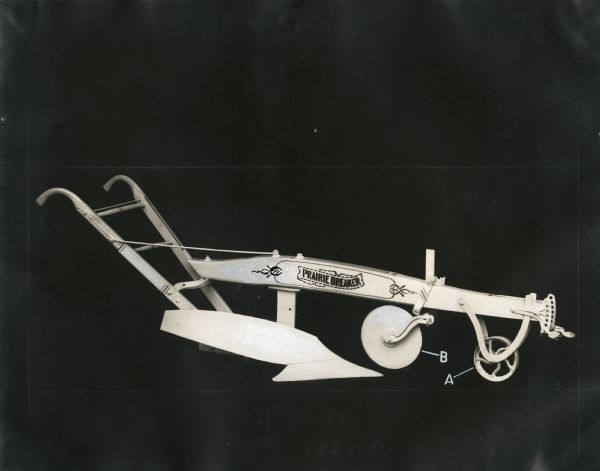 Side view of a Prairie Breaker plow [breaking plow] against a black backdrop. Two parts of the plow are labeled as "A" and "B."