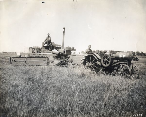 Two men, one using a Deering harvester-thresher, and the other with an International Harvester Titan 10-20 tractor, are working in a field.
