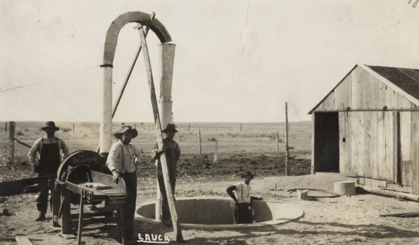 Four men working at a site for the construction of a silo. They are pouring cement for its foundation.