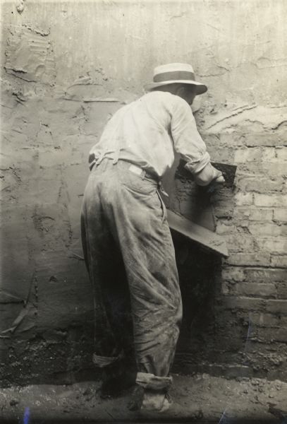 Man spreading cement on the wall of a silo.
