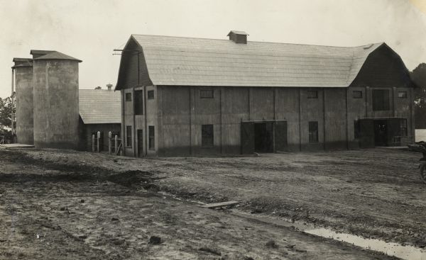 Exterior view of large barn and two silos.