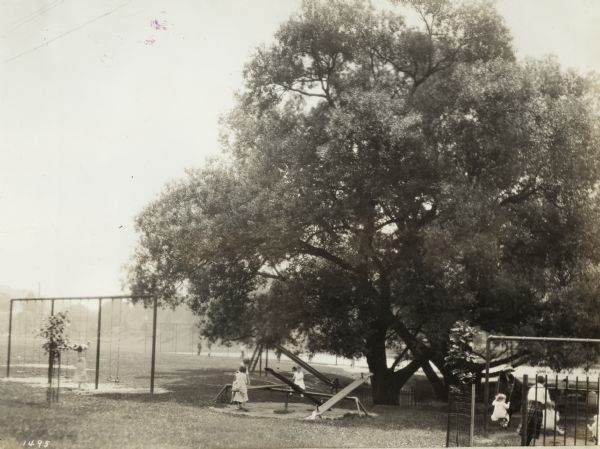 Young children playing at the park. Original caption reads: "Beacon playground — about 800 daily attendance. Splendid arrangement of playground and athletic activities — ball diamonds and tennis courts."