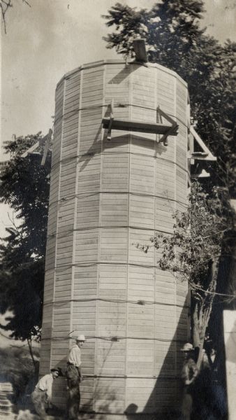 Three men working on a multi-faceted wooden(?) silo.