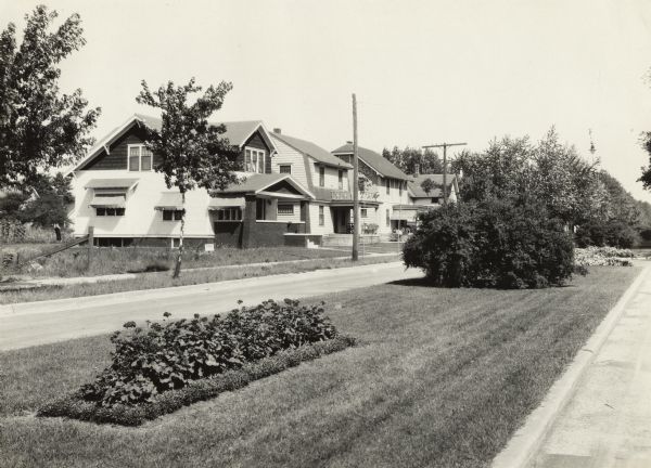 View of the landscaping on a street median in a residential neighborhood. Dwellings are in the background.
