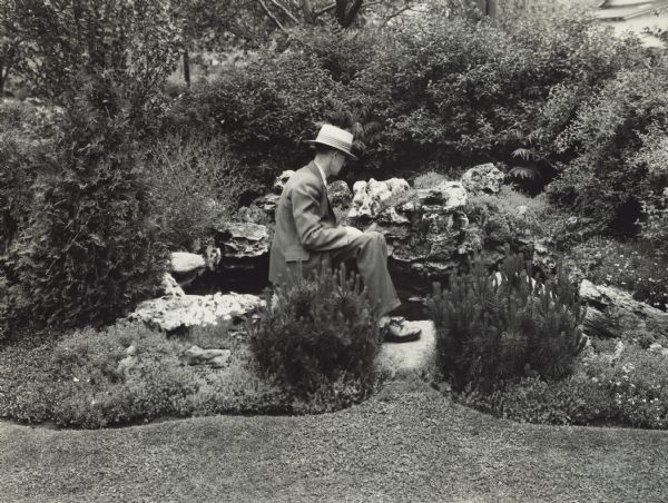 L.A. Hawkins is sitting at a rock and water garden feature at the home of C. Mock Jr., 15 S. Commonwealth Avenue.