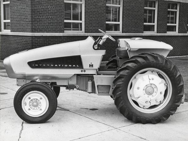 Side view of experimental International HT 340 tractor displayed outdoors near a brick building.