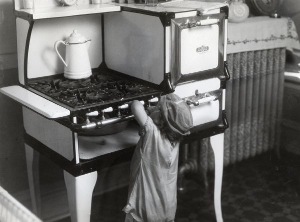 An unattended child turning the knobs of a gas stove in a farmhouse.