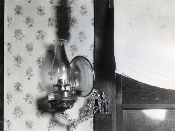 Close-up view of an oil lamp attached too close to the wall of the International Harvester experimental farm so that a trail of soot stains the wallpaper.