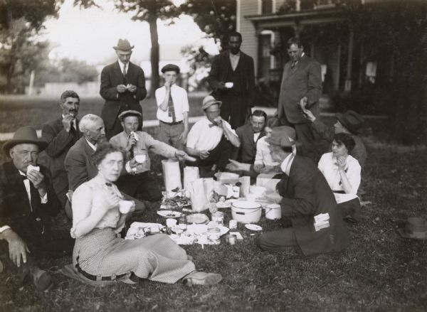 Group of International Harvester Agricultural Extension speakers seated on a lawn for supper. Original caption reads: "This picture shows part of the Alfalfa Crew of Speakers taking supper on the lawn of a farm in Sangamon County, Ill. during the Alfalfa Campaign during 1913."