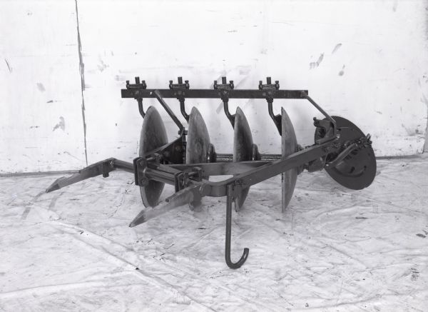 View of an International Harvester C-14-D harrow plow set against a light-colored backdrop.