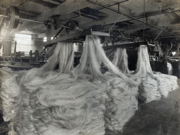 Hemp or sisal fiber piles on the floor of International Harvester's McCormick Twine Mill as it is processed through spreading machines. The mill was located on the grounds of the McCormick Works (factory).