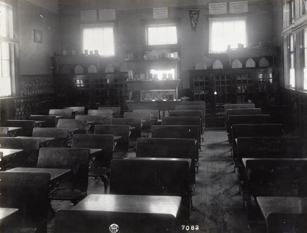 Interior view of an empty classroom in rural school. Original caption reads: "No city school can excel this two-roomed school... Miss McMahon, teacher."