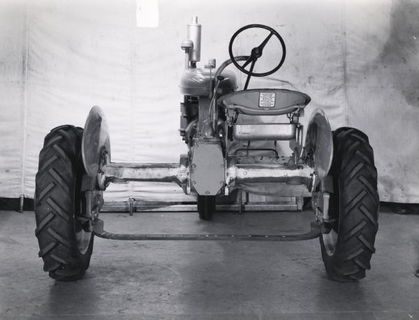Studio shot from rear of a Farmall B tractor showing seat decal. The tractor may be experimental. A white backdrop is in the background.