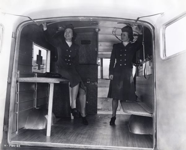 Two uniformed TWA Hostesses, Ruth Ellison and Eula Walker, examine the interior of an International D-15-M (Metro) truck sold to Czechoslovakian Relief for service with the Czechoslovakian Army in England.