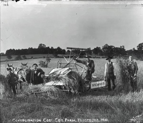 Group of men from the Consolidation Coal Company pose with a McCormick grain binder and two horses in a field on the company farm.