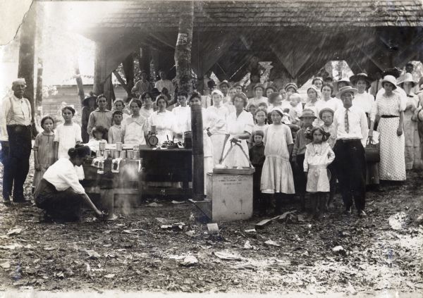 Lula Tunisson using an El Flo hot water canner to give a presentation to the men, women, and children of a canning club.