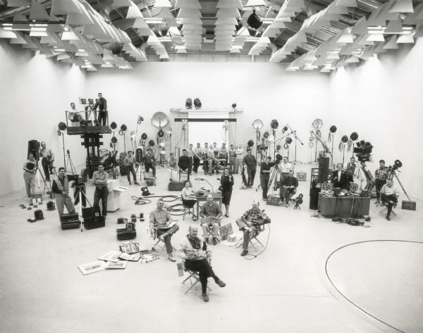 A large group of photographers, filmmakers, and other individuals gathers for a portrait in International Harvester's Hickory Hill Farm photo studio.